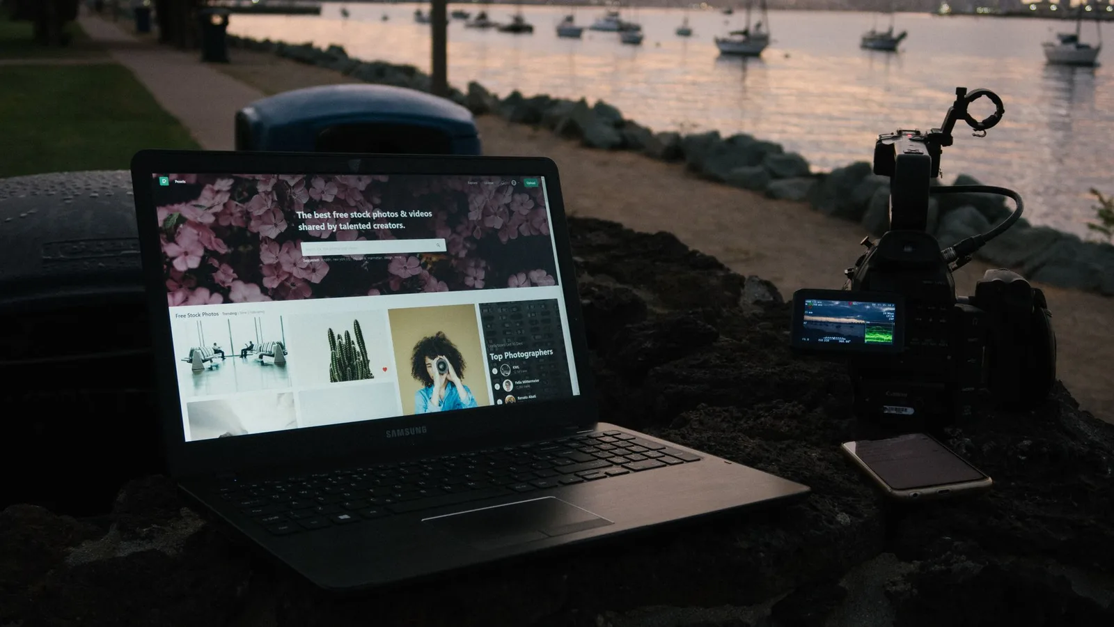 A laptop, camera and phone on a waterfront table after a photography session