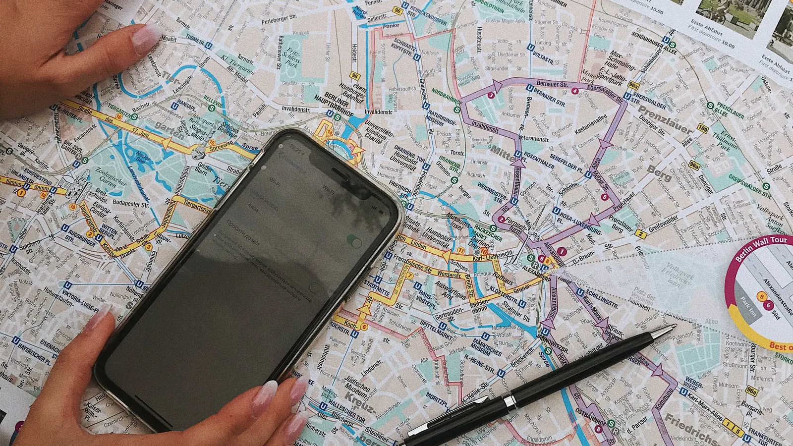 Hands holding a smartphone over a paper city map before removing GPS data from a photo