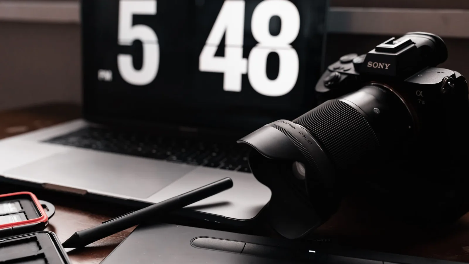 A camera, laptop, and memory card case on a desk for reviewing photo files