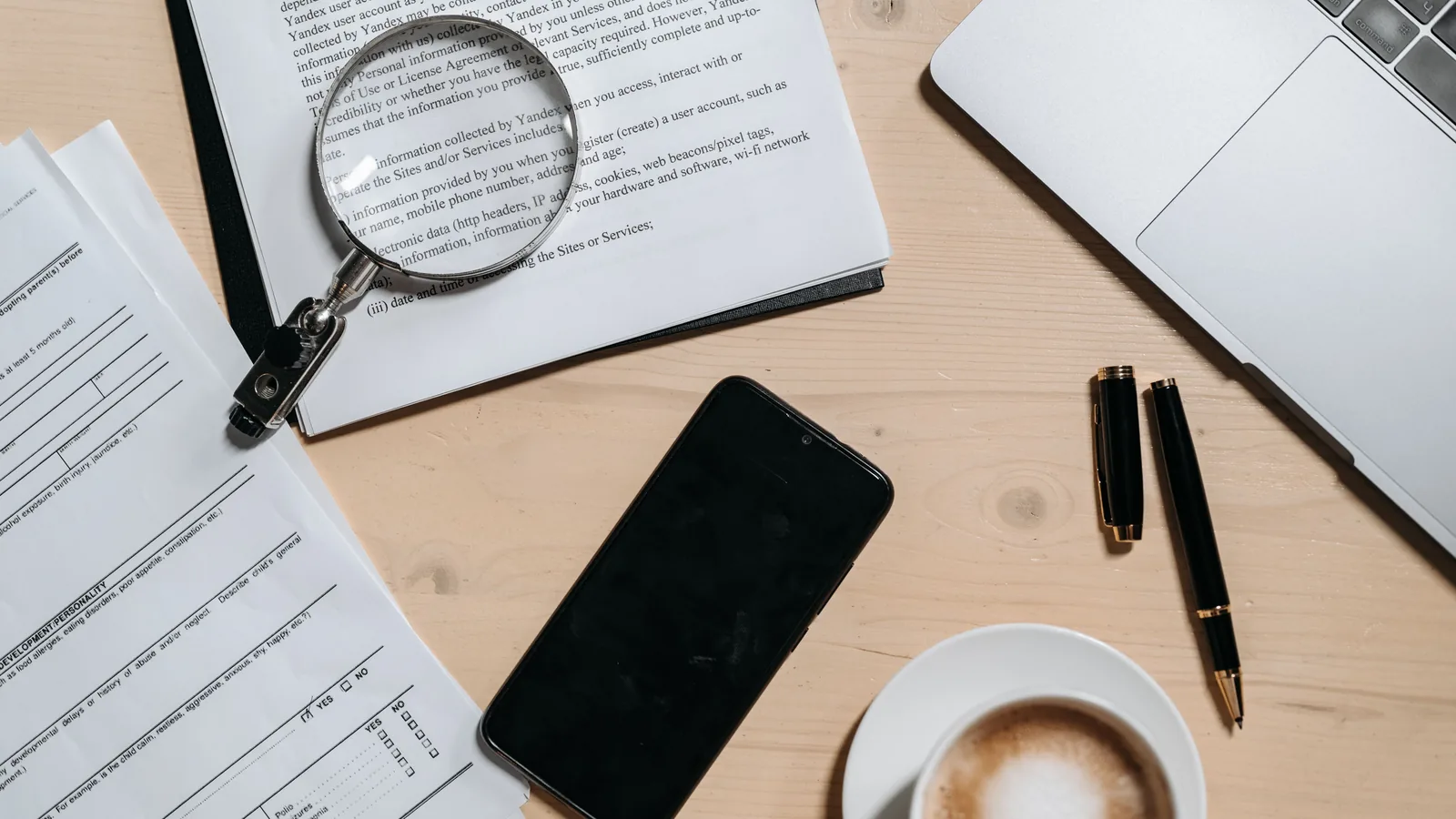 Documents and a laptop on a desk before removing metadata from a PDF file